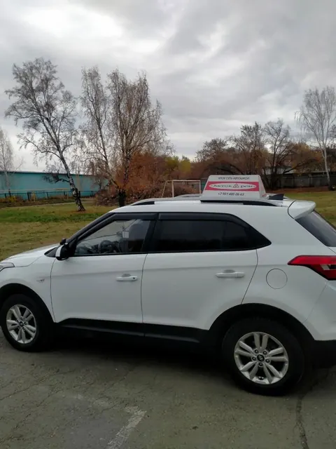 Белый учебный автомобиль со знаком на крыше